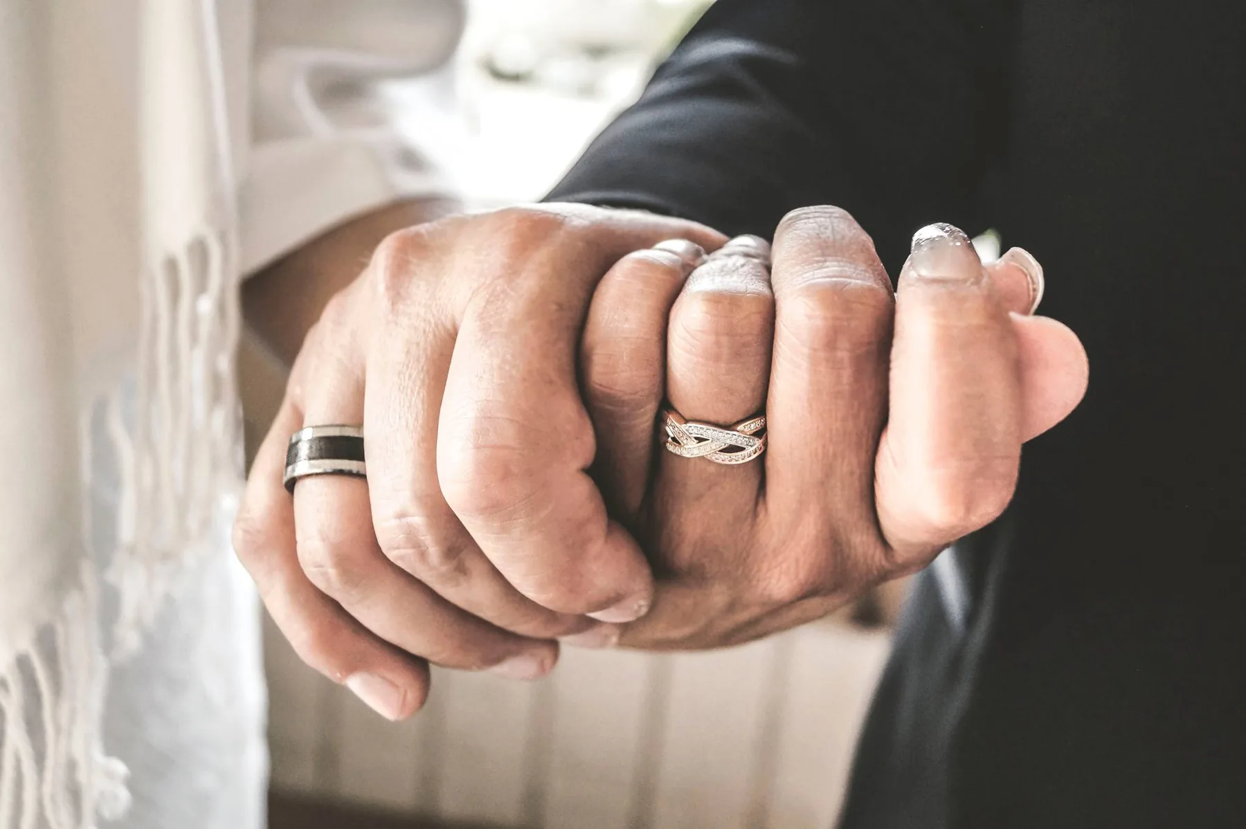 Groom holding the bride's hand, wedding bands showing