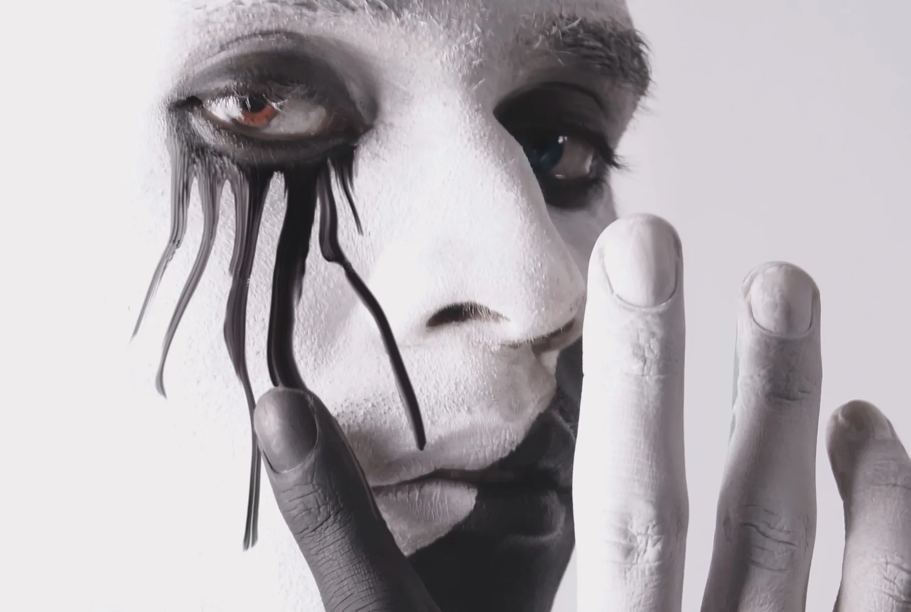 Close-up of a painted face with black tendrils running from the eye