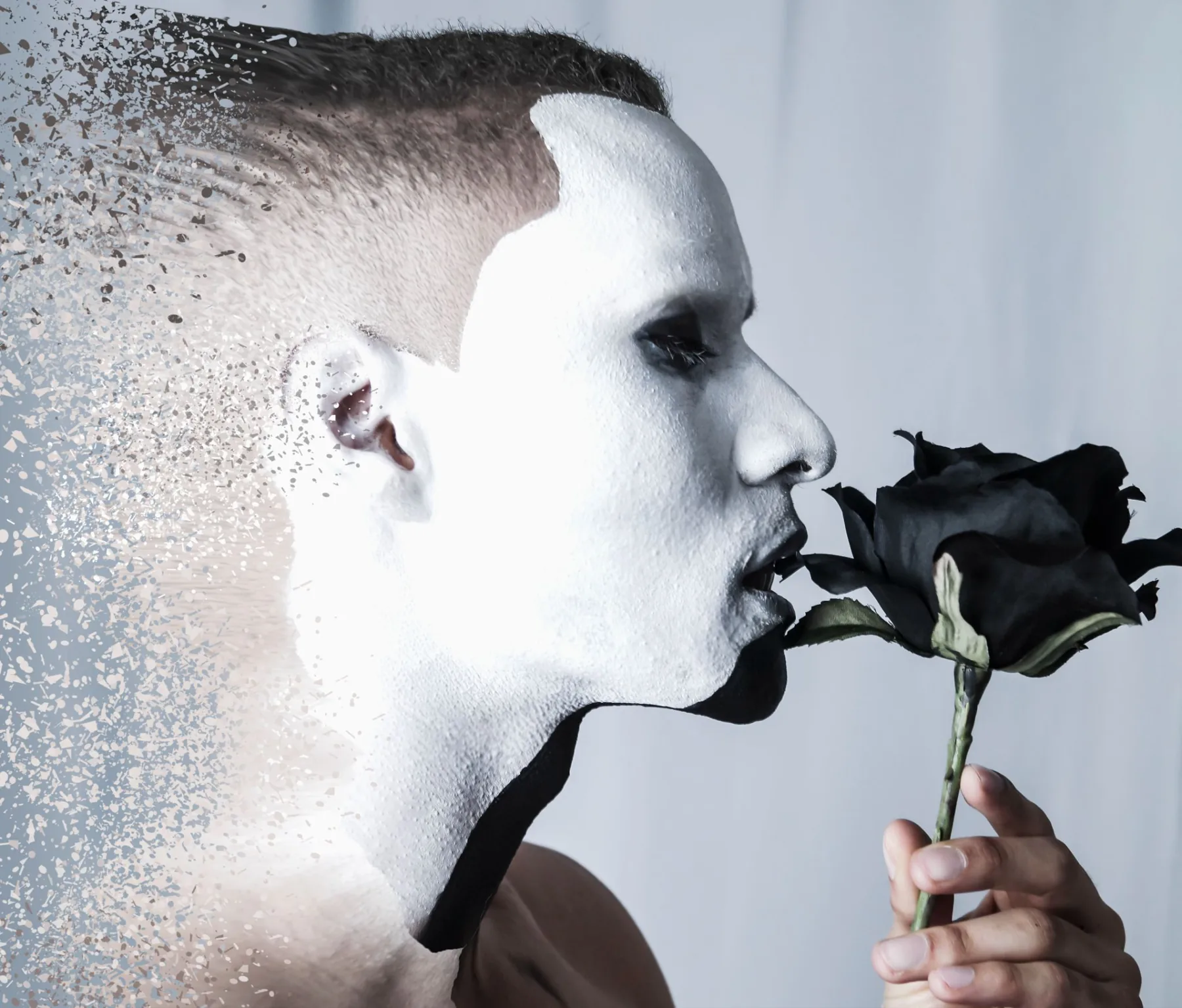Man in white face paint holding a black rose, dispersion effect